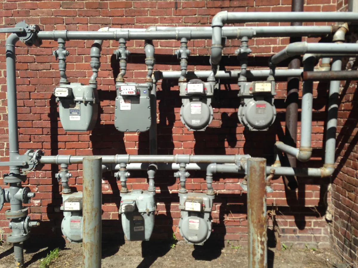 A bank of natural gas meters on the outside wall of a commercial building